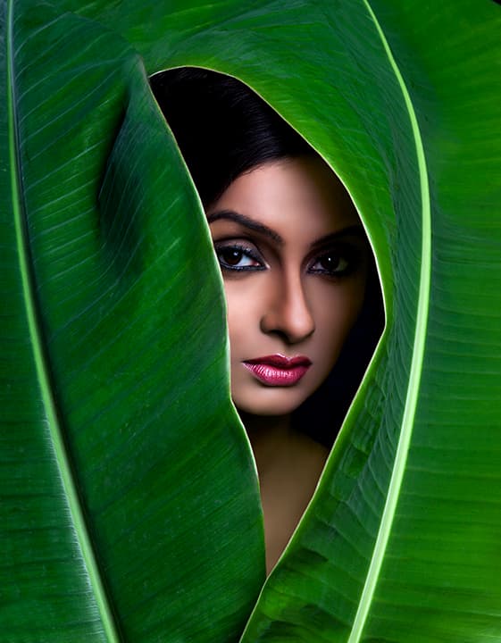 Face framed inside curling banana leaves