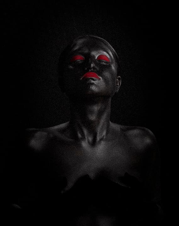 Body paint, eyes closed, red lips in darkness