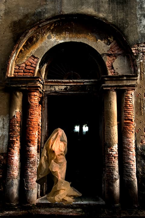 Amber-shrouded figure in a decayed Kolkata doorway