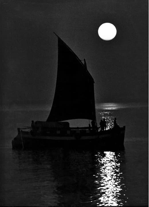 Sailboat and crew under a full moon